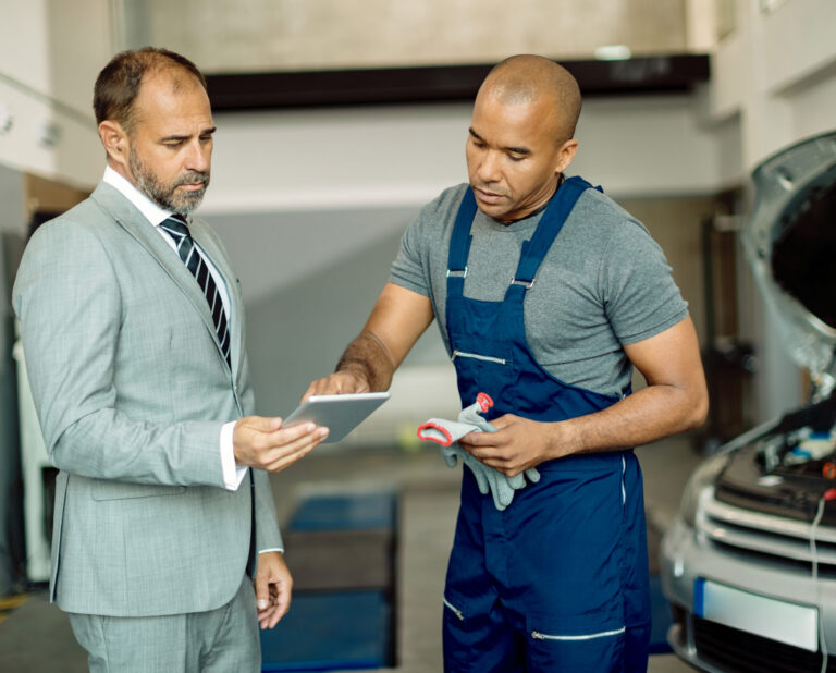 black mechanic his manager working touchpad auto repair shop